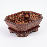 Artisan painting the pattern on a red Delapan wooden bowl · KI-generierte Szene